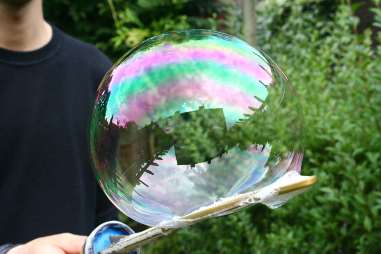 someone holding onto a soap bubble with the shape of a house in it