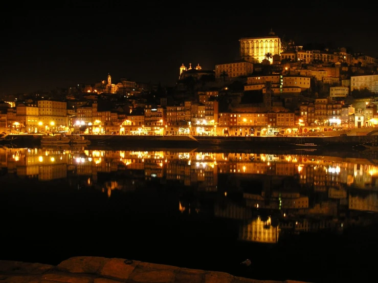 the night view of buildings on a hill from across a lake