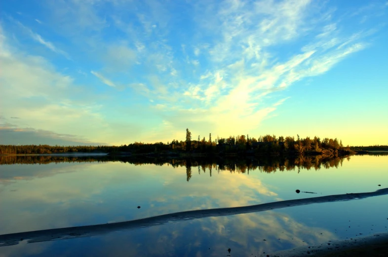 a body of water with some trees and a blue sky