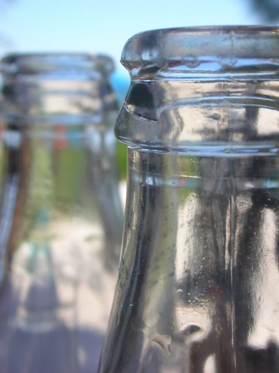 three shiny glass bottles are sitting on a table