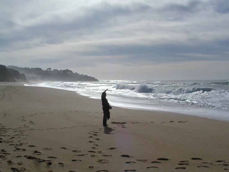 a person walking down the beach with footprints