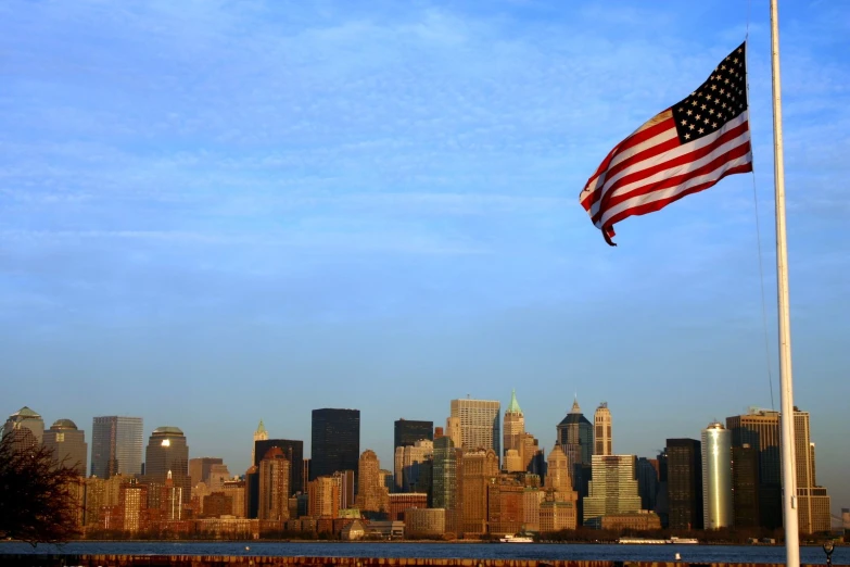 an american flag is flying in the foreground, with a large city in the distance