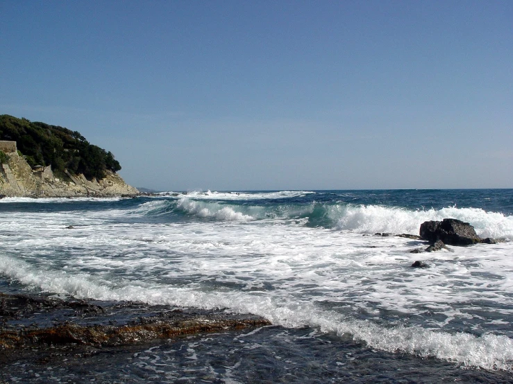 waves rolling in to shore by an old cliff