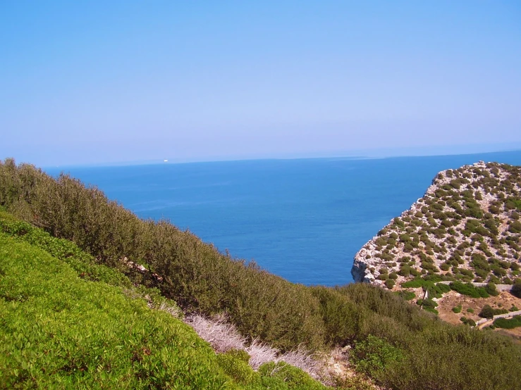 a grassy hill next to a blue ocean