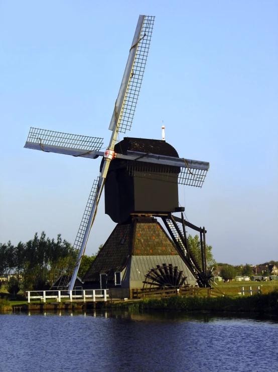 an old windmill sits near the water