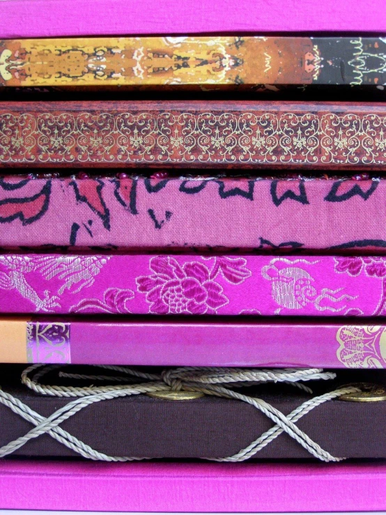 some books stacked up next to each other on a pink background