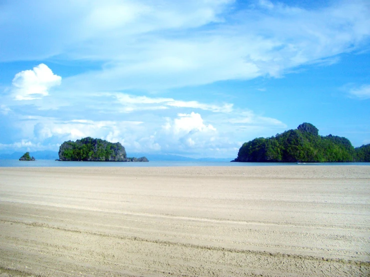 a sandy beach with small islands in the ocean