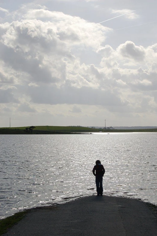 a person standing on the end of a large body of water