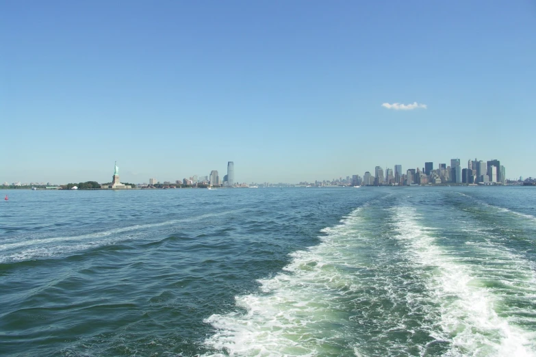 a boat traveling through the water with cityscape in the background