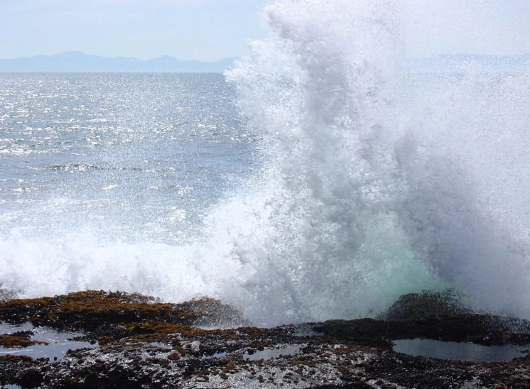 a wave crashes over the rocks along a beach