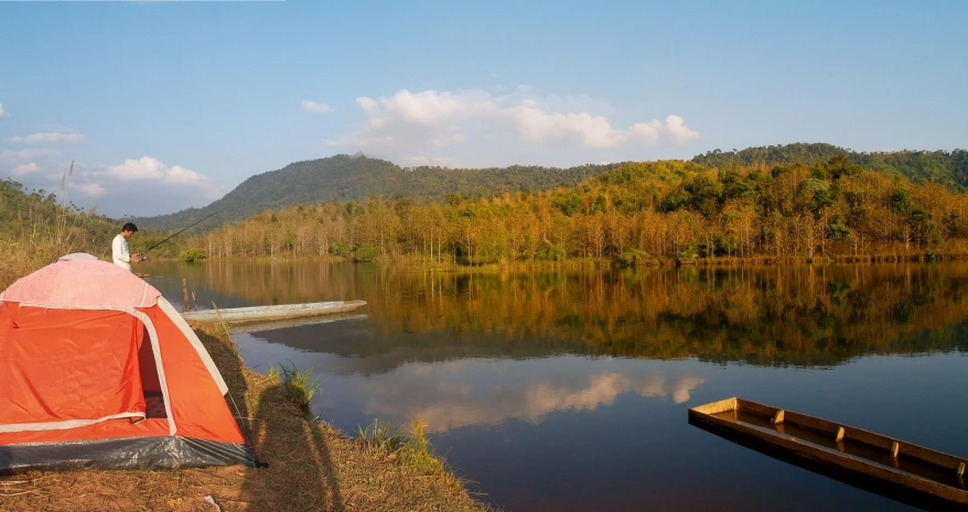 an orange tent on the shore of a lake