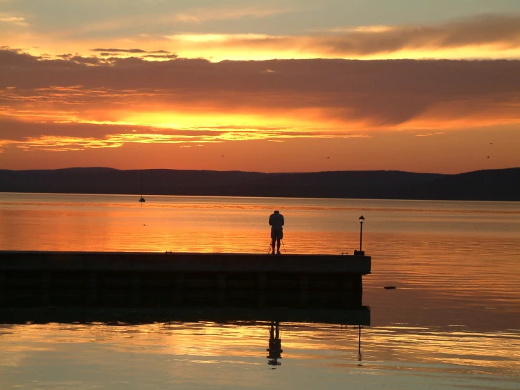 a person is watching the sun set over the ocean