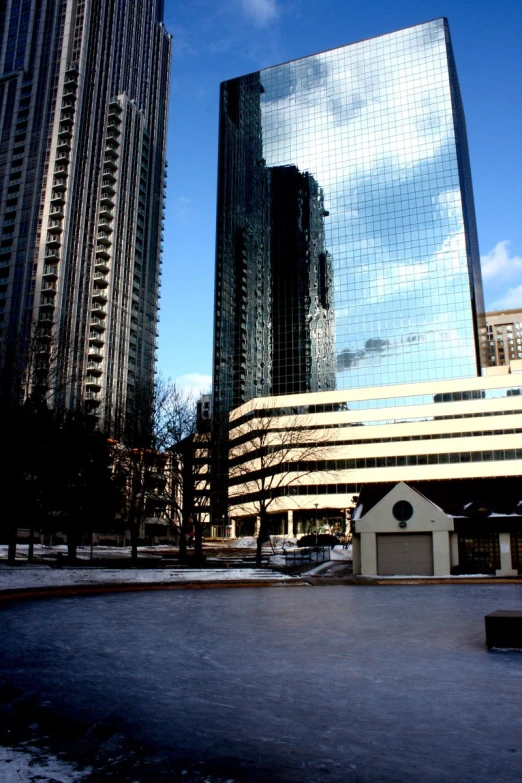 a building near a park is reflecting its surroundings