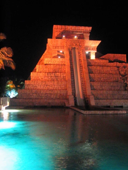a swimming pool lit up at night with the lights on