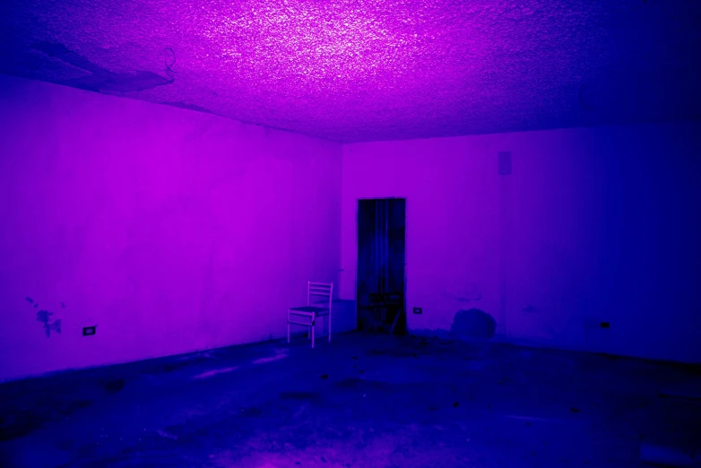 a purple lit room with a chair against a wall