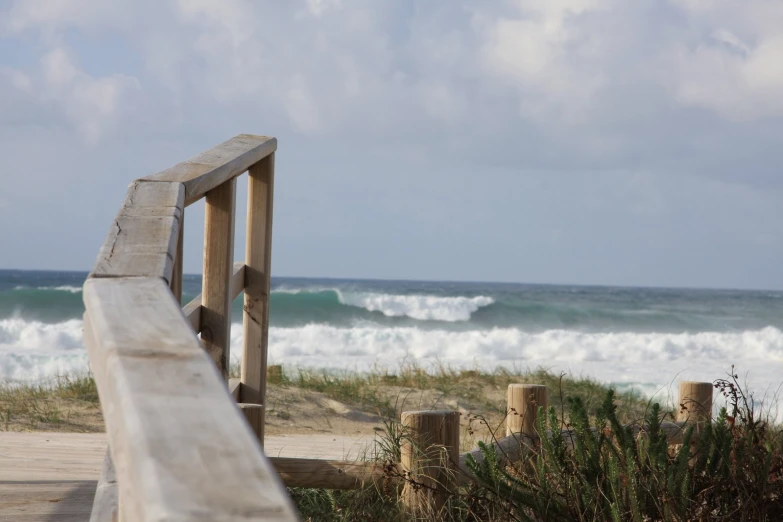 a bench on a boardwalk by the beach