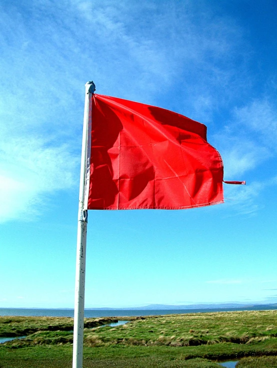 a red flag is shown flying on a pole