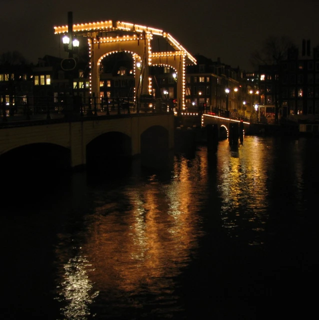 an illuminated bridge spanning over a city on a river at night