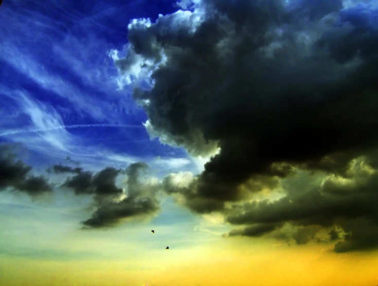 a cloud filled sky over some small buildings