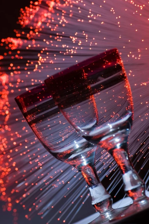 two champagne glasses with bright red bubbles in the background