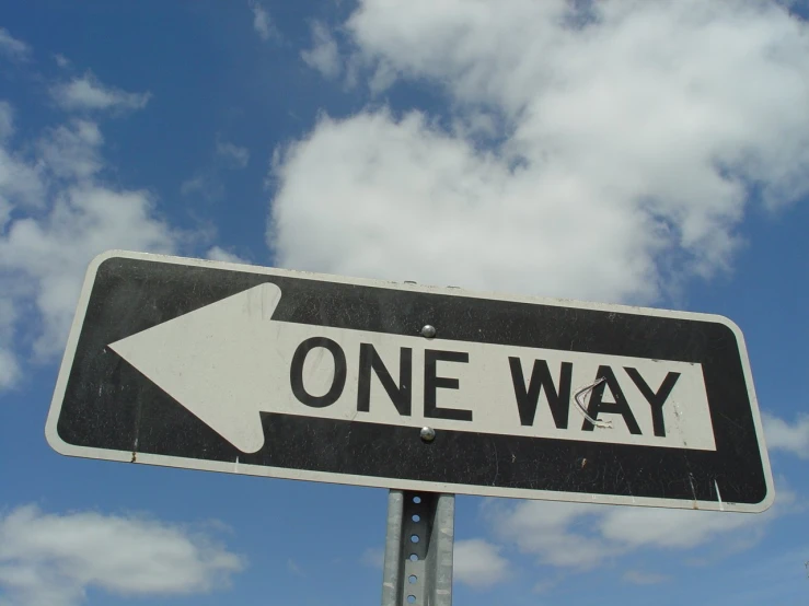 one way sign against a cloudy blue sky