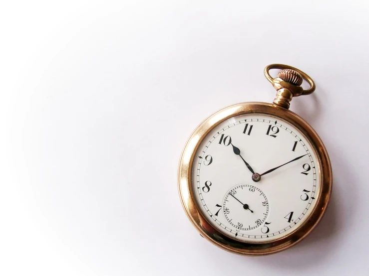 an antique pocket watch is displayed on a white surface