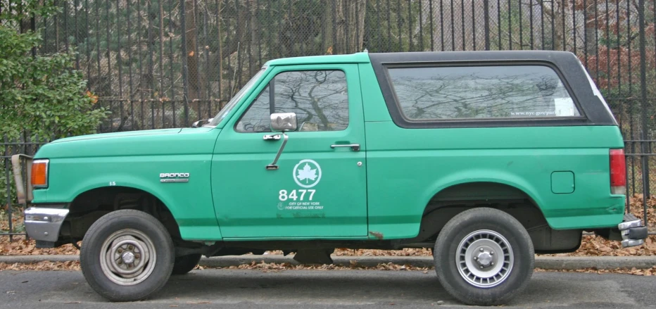 a green truck sitting on the side of the road