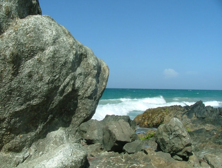 a large rock that is on the beach by the water