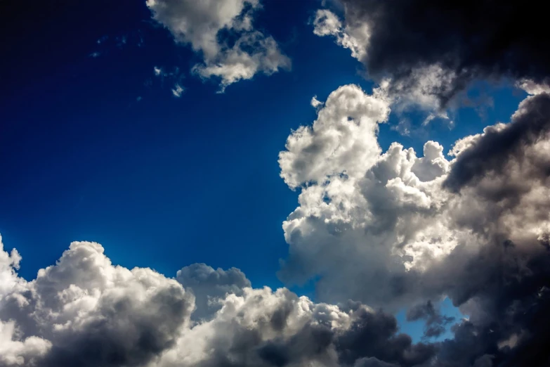 a clear sky with white fluffy clouds that are partially covered by dark