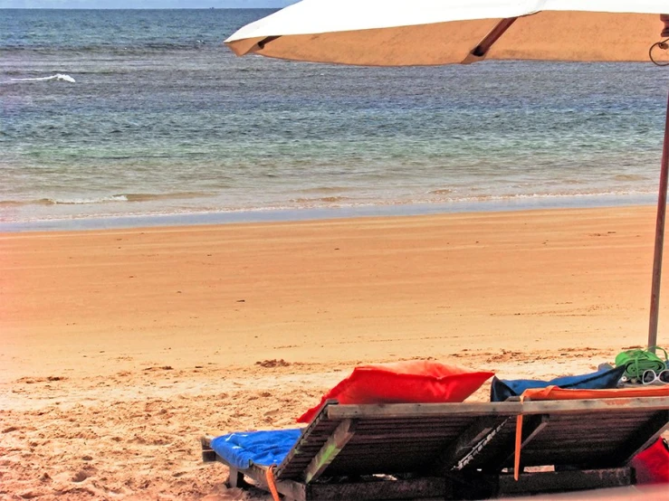 a view of a beach that has an umbrella and chairs in the sand