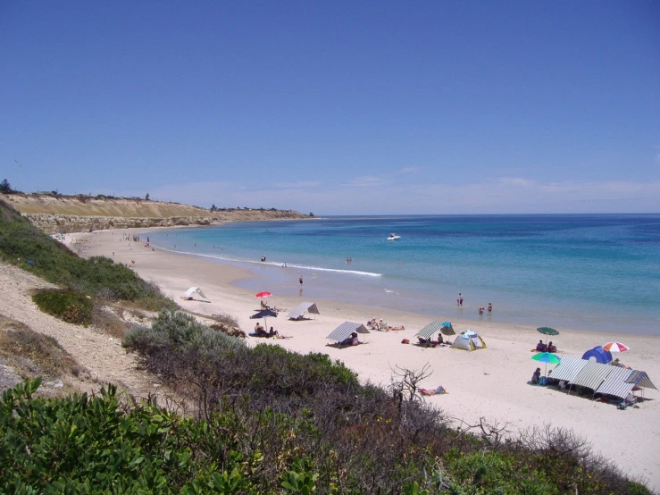 people in the beach with beach chairs and umbrellas