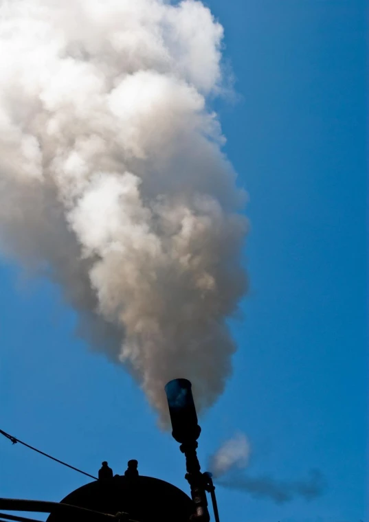 a smokestack emits steam into the sky