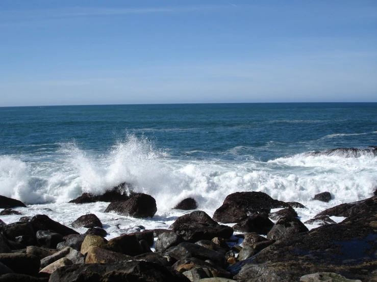 a beach with a lot of rocks and water crashing into it