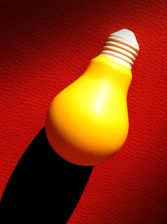 an illuminated yellow light bulb on top of a red sheet