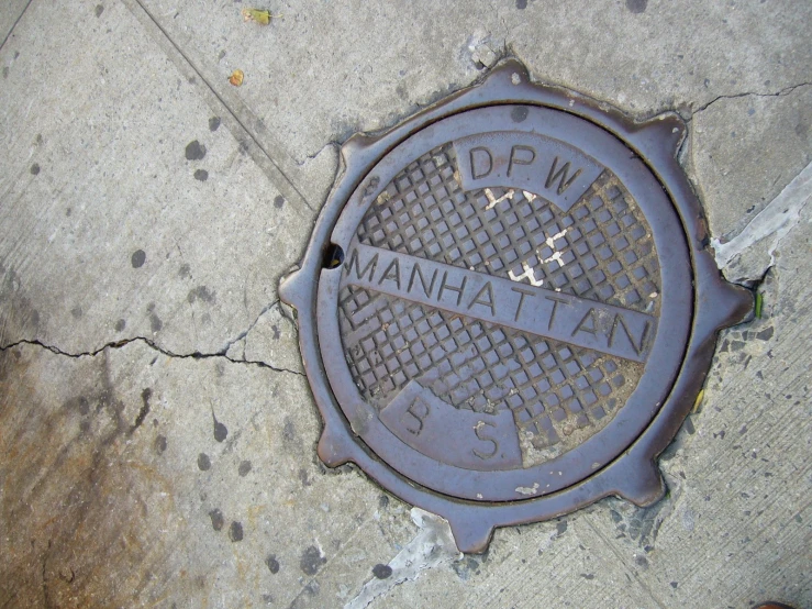an iron manhole cover sitting on the sidewalk
