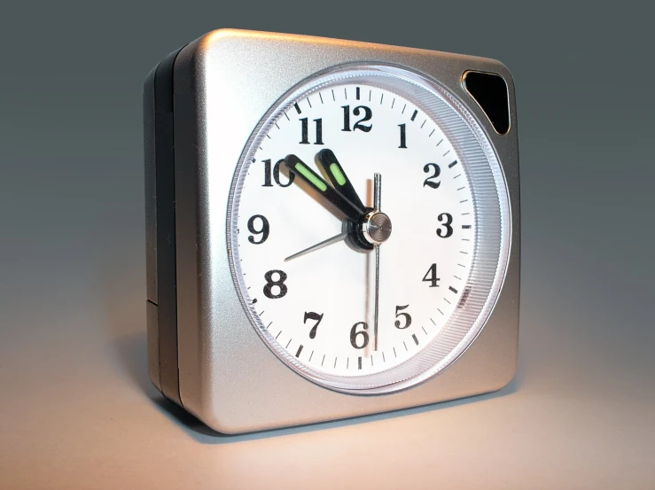 a shiny metal clock with black hands