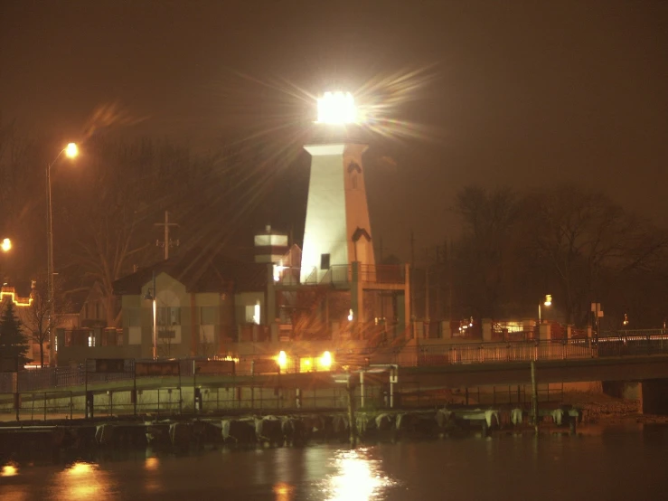 a white lighthouse sitting on the side of a lake