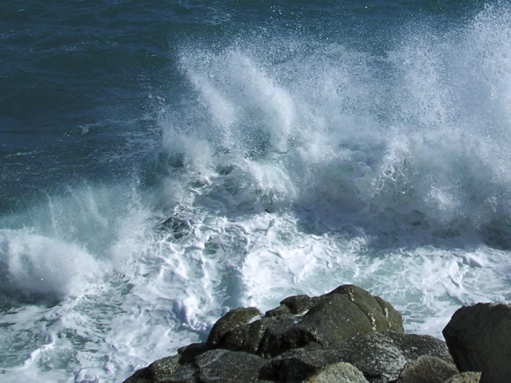 a large wave crashes on the rock and into the ocean