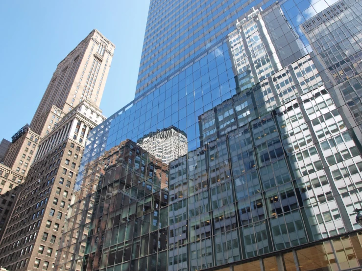 tall buildings are reflecting in the mirrored glass windows of other buildings