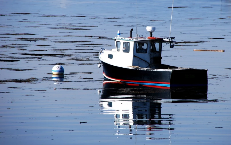 a fishing boat in the water surrounded by land