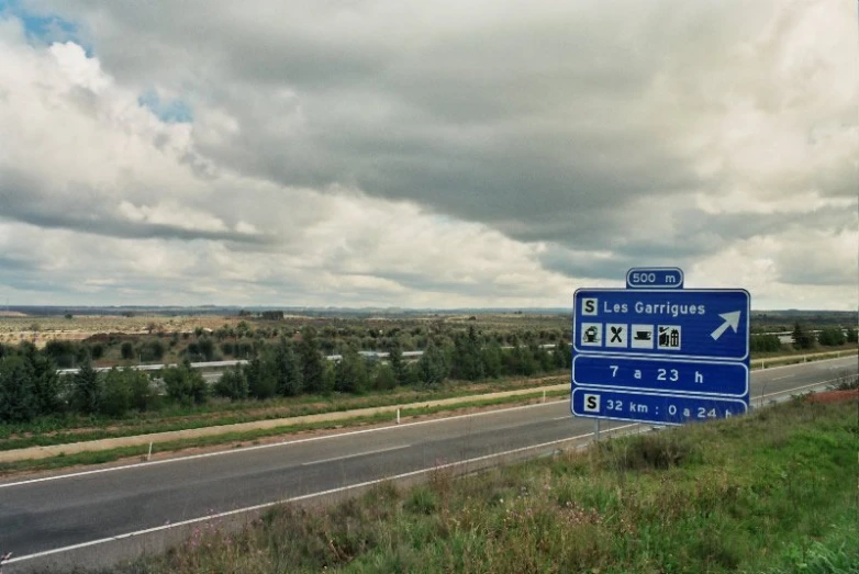 blue and white street sign in front of an empty highway