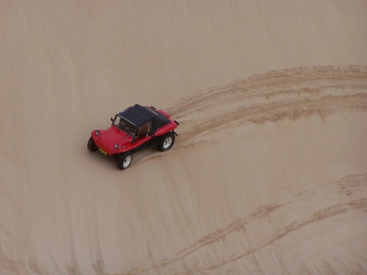 a toy jeep is driving through sand dunes