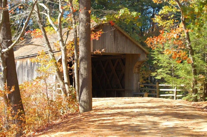 a wooden covered bridge over a dirt road