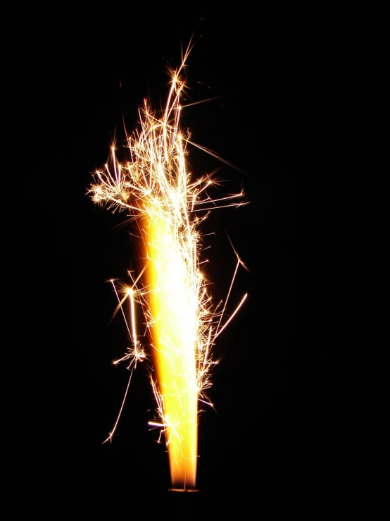 a yellow and red sparkler lit up on a black background