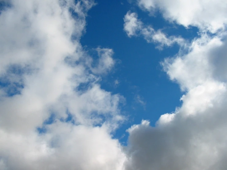 the clouds in the blue sky are forming an arch