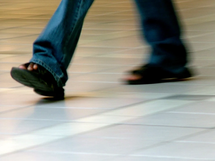 a persons feet, standing on tile in an office building