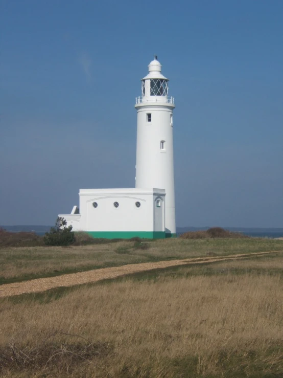 a white lighthouse on top of a hill with a path leading to it