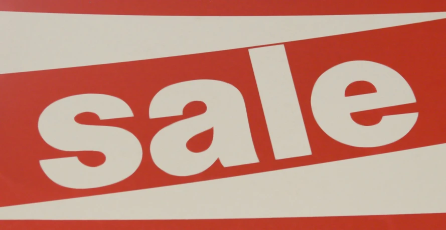a white and red sale sign sitting on top of a table