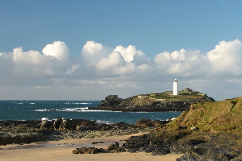 a lighthouse next to the ocean and a cloudy sky