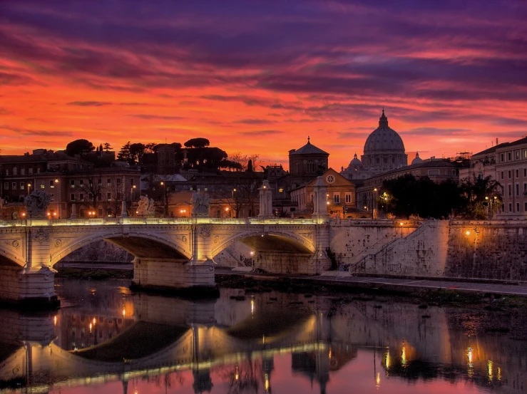 a large bridge over a river under a sunset sky